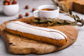 Glazed eclair dessert with coffee on wood