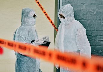 Forensic investigators collecting evidence at a murder scene in a building with barrier tape....