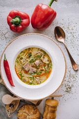 Chicken soup with noodles and vegetables in white bowl