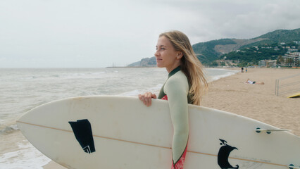 Happy smiling authentic young woman with surfboard look at camera, smile confident and giggle. Summertime adventure, vacation destination lifestyle of surfing in California vibes