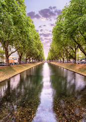 Fototapeta na wymiar Konigsallee - a popular tourist and historical attraction of the city of Dusseldorf in Germany. A canal planted with plane trees with fashionable shopping galleries