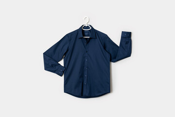 The front view of a dark blue colored button down shirt on a shirt hanger, isolated on white background.