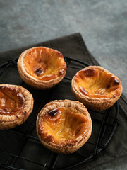 Portuguese eggtart or Egg tart, traditional Portuguese dessert. Served on a white plate. Blurred background and selective focus image.
