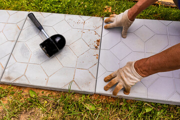 the hands of a worker in gloves lay tiles in a country house, cottage. Landscaping. laying of stone...
