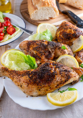 Baked chicken legs with salad and baguette on a dinner table