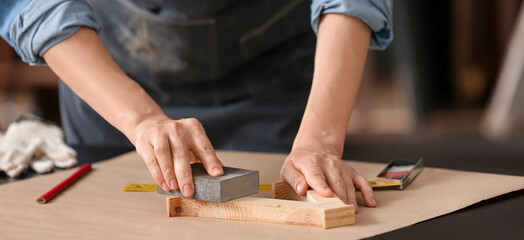 Fototapeta na wymiar Female carpenter smoothing planks in workshop, closeup