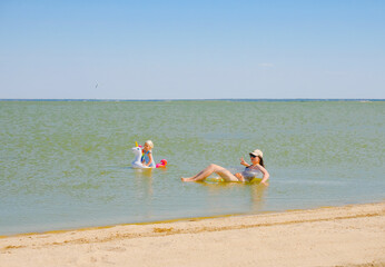 Adults and children swim in the sea on inflatable circles.