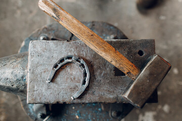 Blacksmith's hammer and horseshoe on metal anvil at forge. Overhead view