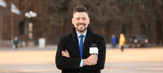 Male journalist with microphone outdoors