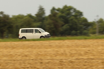 a car driving on the road in the middle of a field, photographed by the panning method