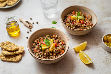 Assiette de salade taboulé aux lentilles, quinoa et crudités sur table
