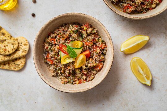 Assiette de salade taboul&eacute; aux lentilles, quinoa et crudit&eacute;s sur table

