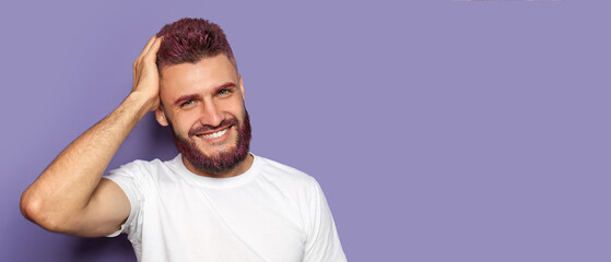 Portrait of handsome man with dyed hair and beard on violet background with space for text