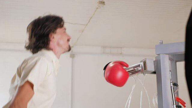 man fights, trains with mechanical robot boxer. Gloved hand. shows language, dodges, funny video