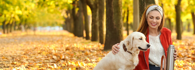Happy woman with her cute dog in autumn park