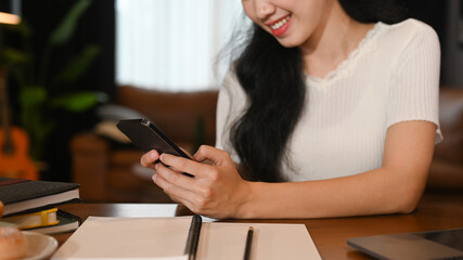 Smiling young woman using mobile phone for chatting with friends. Technology, social network, communication concept