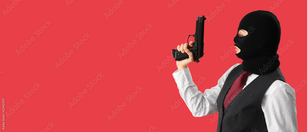 Wall mural Portrait of young woman in balaclava and with gun on red background with space for text