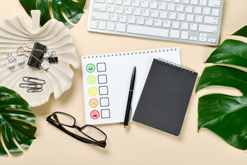 Notebooks with satisfaction rating, pen, eyeglasses and computer keyboard on light background