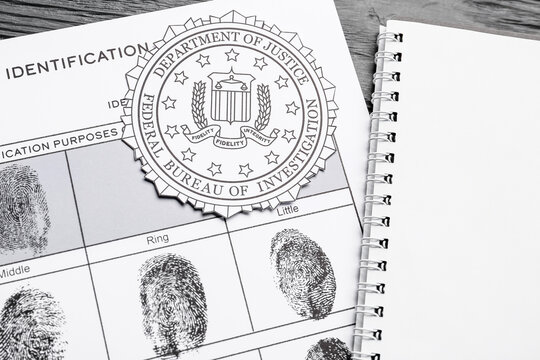 Paper sheet with finger prints, seal of FBI and notebook on dark wooden background, closeup