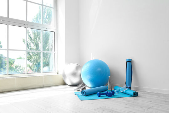 Different sports equipment on floor near white wall in room