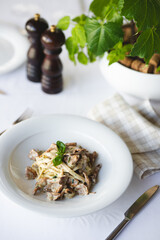 Appetizing Italian pasta with mushrooms on a light background.