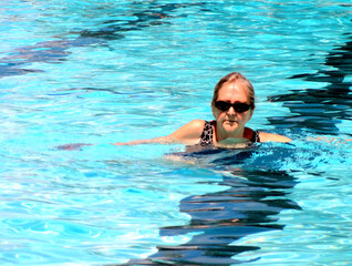 Mature female senior in the swimming pool outside.