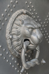 Ancient middle age iron door handle with a lion muzzle and ring, closeup, details.