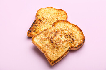 Slices of tasty toasted bread on pink background