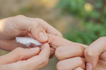 The woman is trying to pull the splinter out of the child's hand. A splinter in a child's hand.