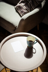 coffee cup and blank card on table in harsh sunlight