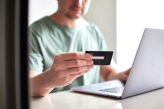 CloseUp von Mann mit Kreditkarte in der Hand benutzt Laptop: Online Shopping, Rechnung bezahlen, Urlaub buchen, Geld Ausgeben, Internet Banking
