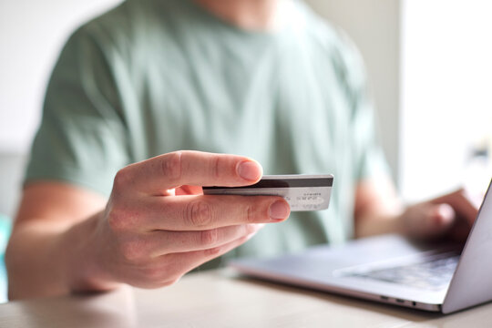CloseUp von Mann mit Kreditkarte in der Hand benutzt Laptop: Online Shopping, Rechnung bezahlen, Urlaub buchen, Geld Ausgeben, Internet Banking
