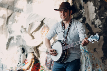 Male musician playing banjo sitting chair indoor.