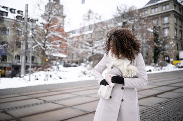beautiful young black woman waiting in front of a theater for here friends in snow covered city