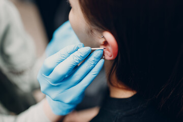 Young woman doing ear piercing at beauty studio salon