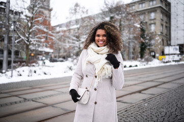 beautiful young black woman waiting in front of a theater for here friends in snow covered city 