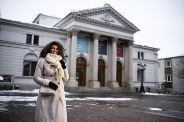 beautiful young black woman waiting in front of a theater for here friends in snow covered city