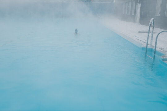 Fit Swimmer Male Training Swim In Open Winter Swimming Pool With Fog. Geothermal Outdoor Spa Health Concept.