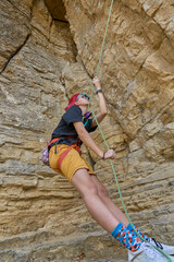 Teenage girl securing her climbing partner by a securing rope system