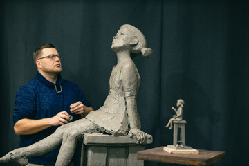 Man sculptor creates sculpt bust clay human woman sculpture. Statue craft creation workshop. Small business.