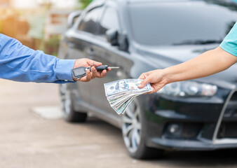 Close up saleman give car key and recieve dollars money from customer.