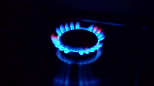 Gas cooktop burning gas stove with blue flame ignited and keeps burning in slow motion