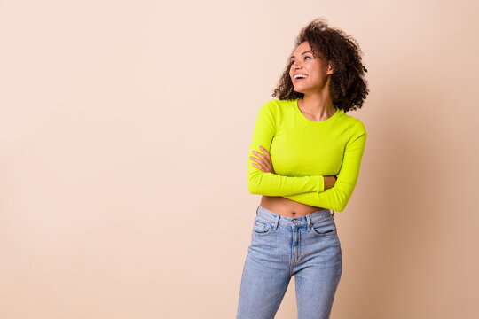 Photo of charming pretty girl dressed neon shirt looking empty space arms folded isolated beige color background