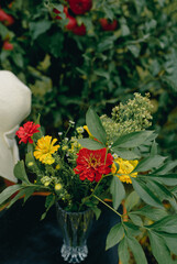 A small summer bouquet of yellow and red flowers found in the garden. Photo on a background of greenery.