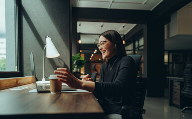 Cheerful businesswoman attending an online meeting in the morning