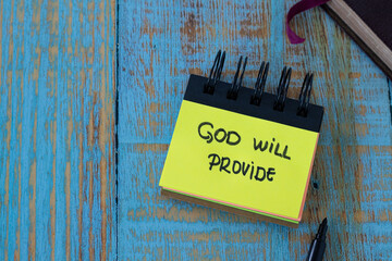 God will provide, a handwritten text note in a small notebook with a closed Holy Bible Book on a...