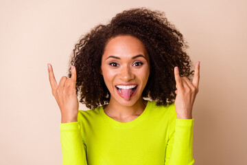 Close up photo of young nice woman curly hair show double horns tongue out dressed stylish yellow outfit isolated on beige color background