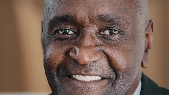 Closeup male portrait headshot face with wrinkles African American adult 60s old senior mature businessman in formal suit elderly citizen man looking at camera smiling with toothy smile posing indoors