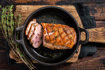 Duck breast roasted in a pan, poultry meat steak with herbs. Wooden background. Top view