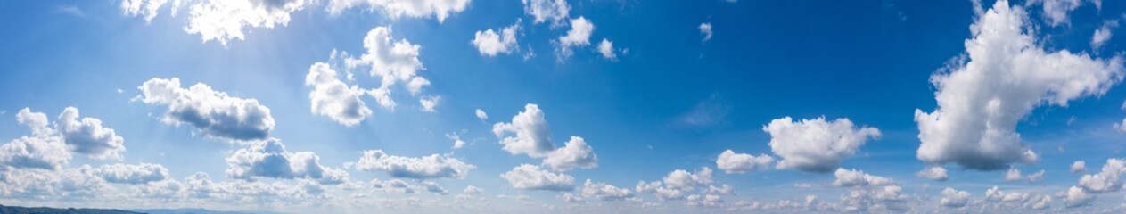 Naklejka na ściany i meble Panoramic view of blue sky with fluffy clouds